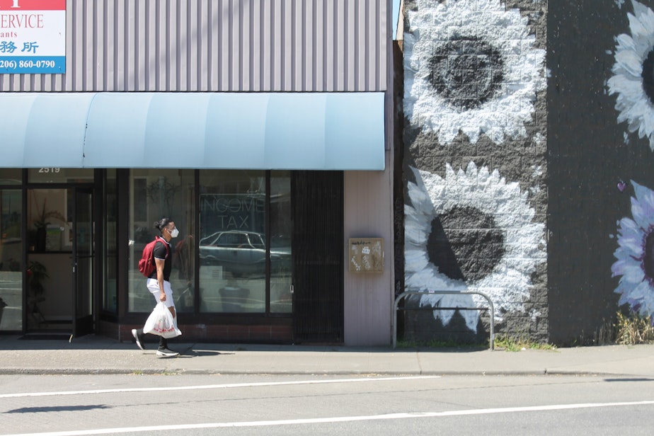 caption: A customer from the Hilltop Red Apple Market walks in Beacon Hill on Friday June 26, 2020.