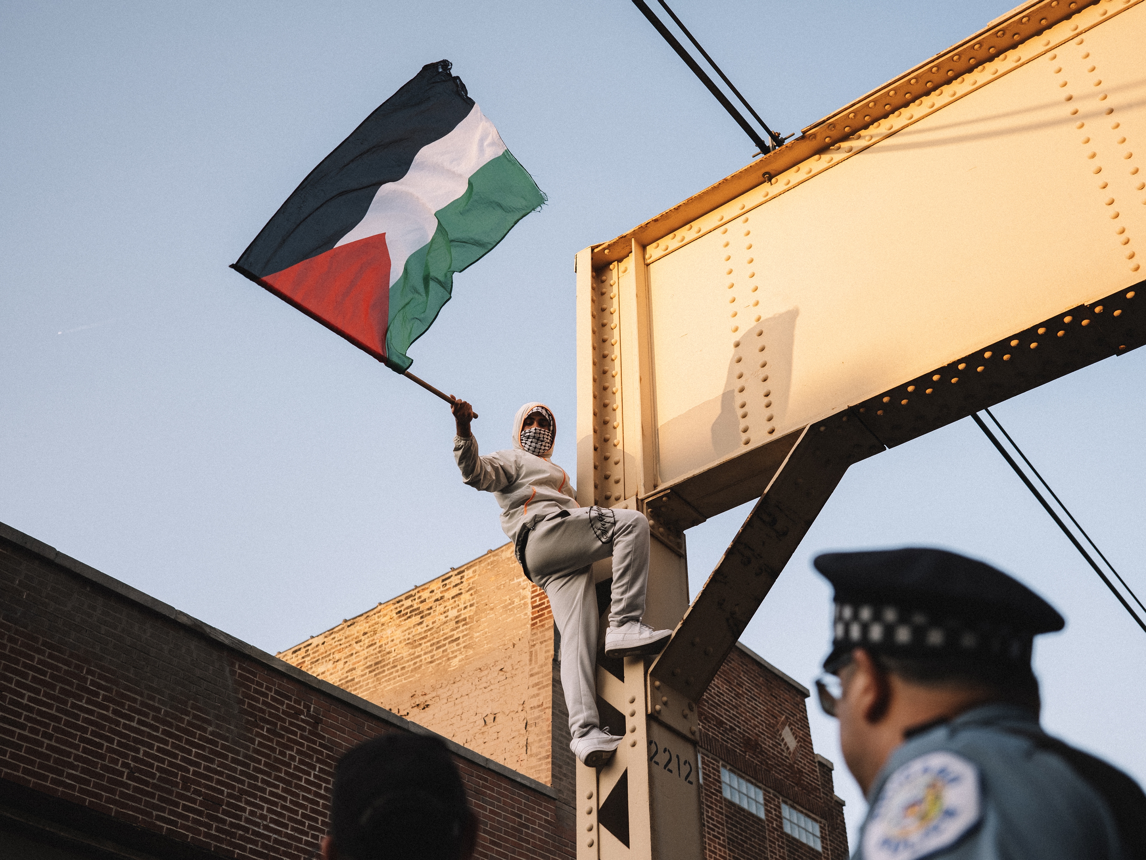 caption: A Pro-Palestinian protester climbs a support beam near the United Center on Wednesday.