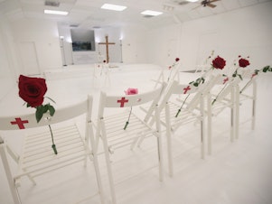 caption: The First Baptist Church of Sutherland Springs was turned into a memorial to honor those who died in November 2017 in Sutherland Springs, Texas. Twenty-six white chairs mark the location where each victim was killed.
