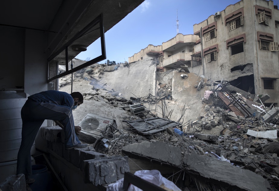 caption: A Palestinian man inspects the damage of a six-story building destroyed by an early morning Israeli airstrike, in Gaza City on May 18, 2021.