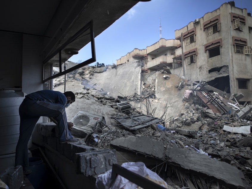 caption: A Palestinian man inspects the damage of a six-story building destroyed by an early morning Israeli airstrike, in Gaza City on May 18, 2021.