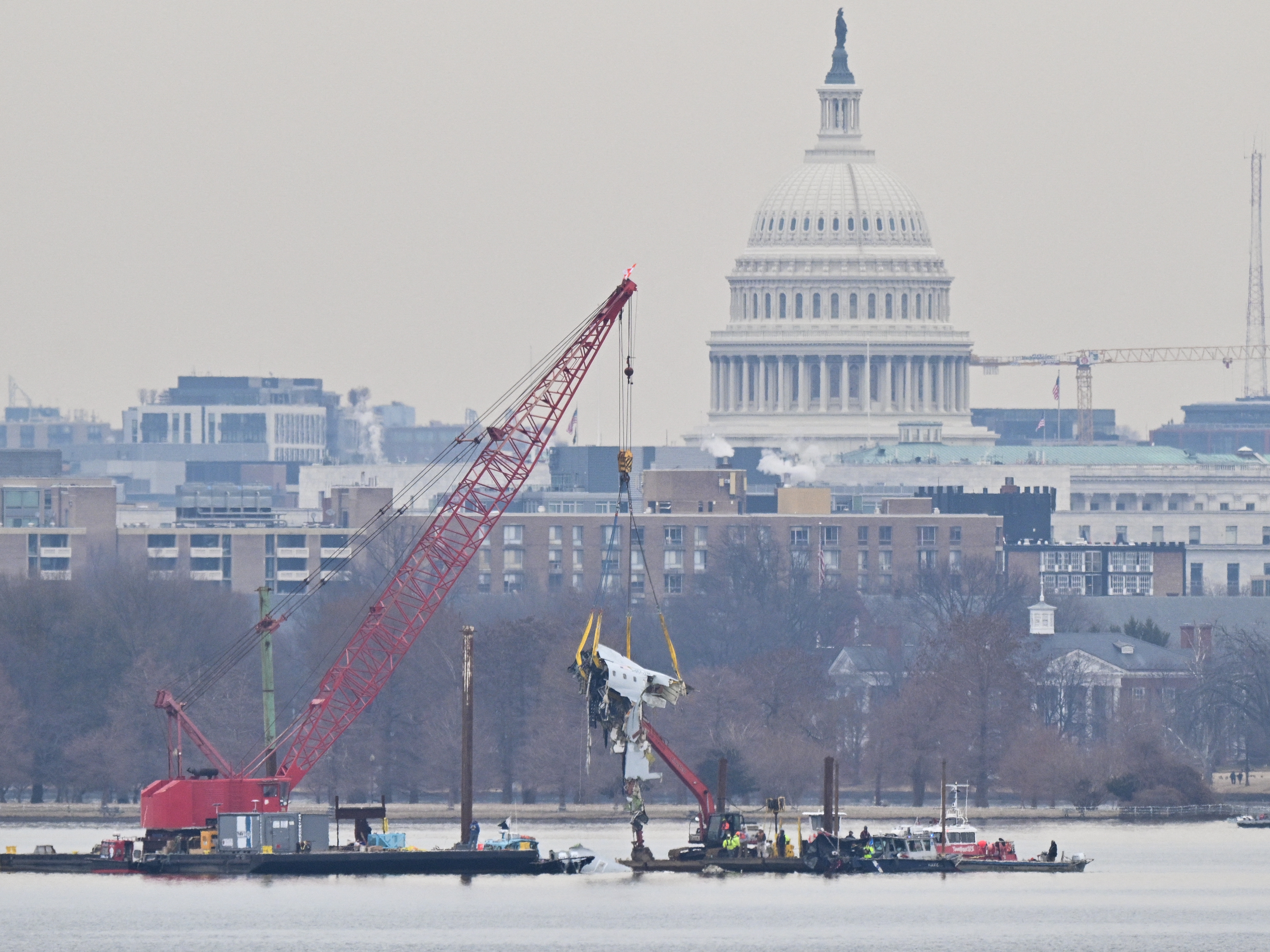 caption: On Feb. 3, a crane removes airplane wreckage from the Potomac River, where American Airlines Flight 5342 collided with a U.S. Army Black Hawk helicopter near Ronald Reagan Washington National Airport in Virginia. All 67 people aboard both aircraft died in the collision as the jet was attempting to land.