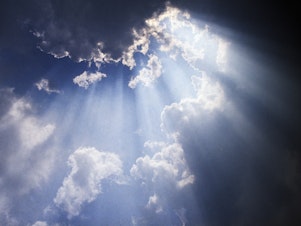 Shafts of sun ray light breaking through cumulus cloud