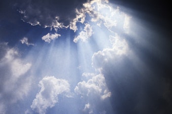 Shafts of sun ray light breaking through cumulus cloud