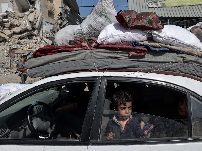 caption: A young boy looks out from a car as members of a Palestinian family leave Rafah in the southern Gaza Strip with personal belongings on March 31.