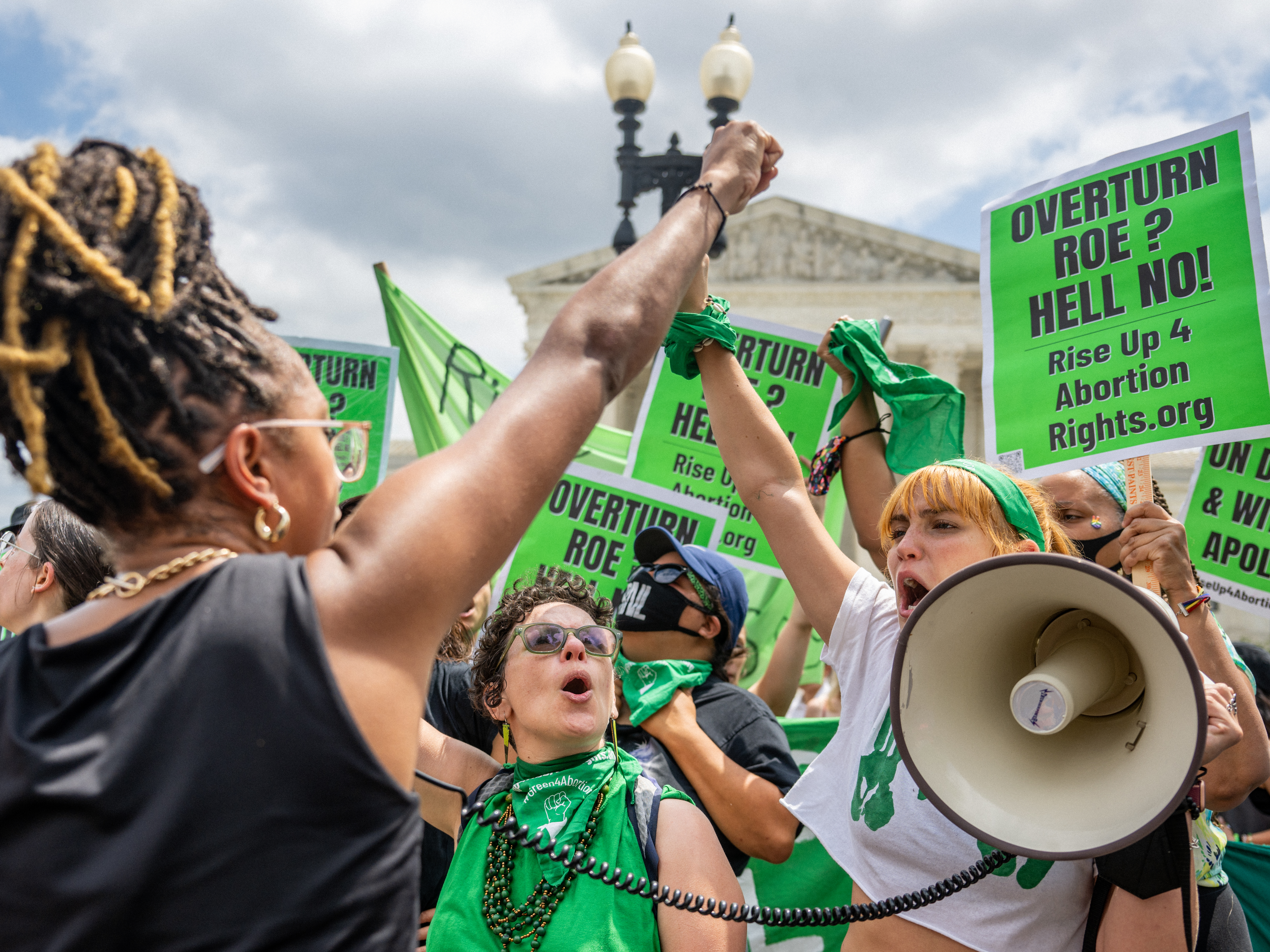 caption: Abortion rights activists clad in green and carrying green signs protest outside the Supreme Court on Saturday.