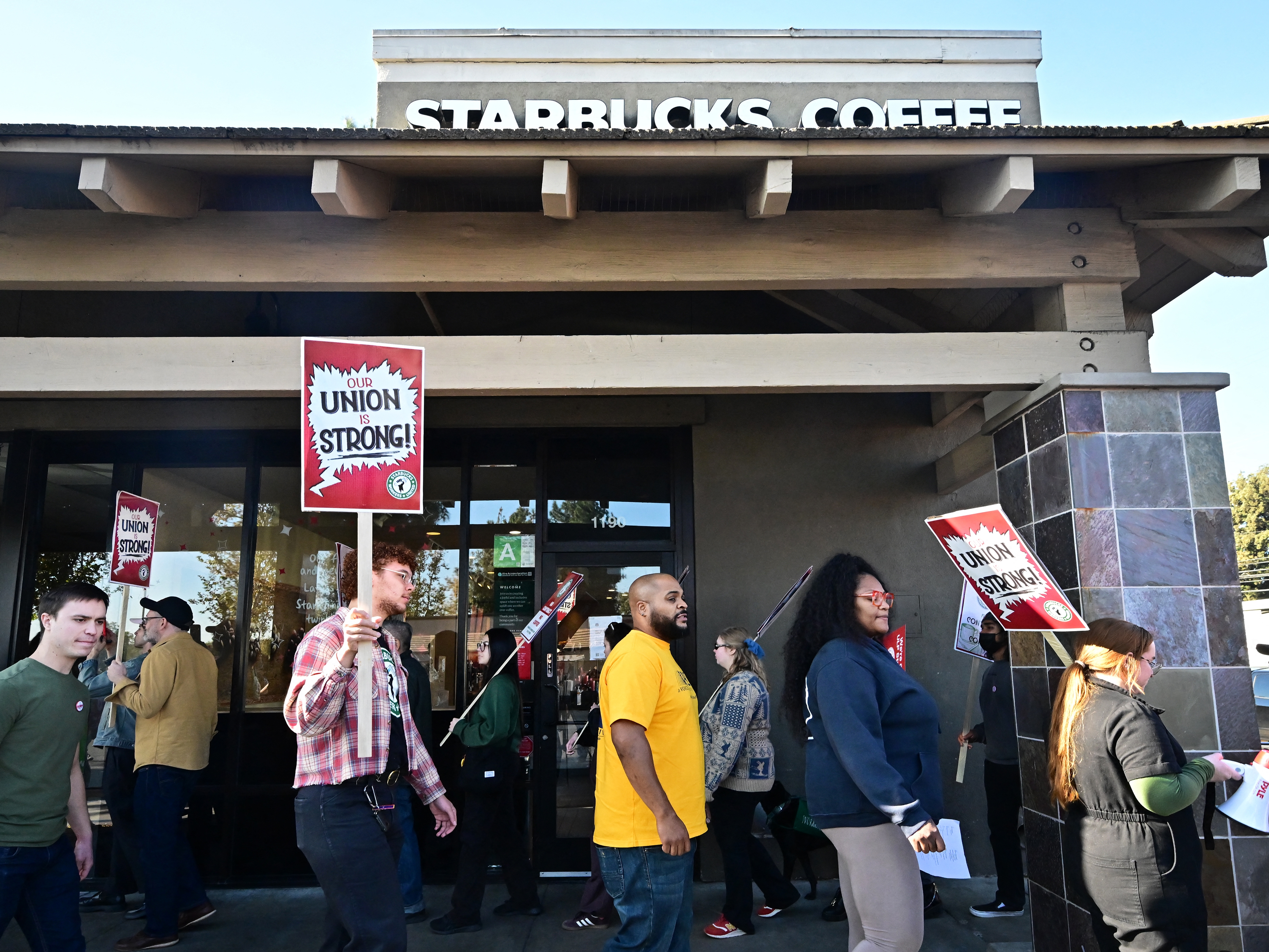 caption: Starbucks workers hold signs as they picket in Burbank, Calif., on Friday.