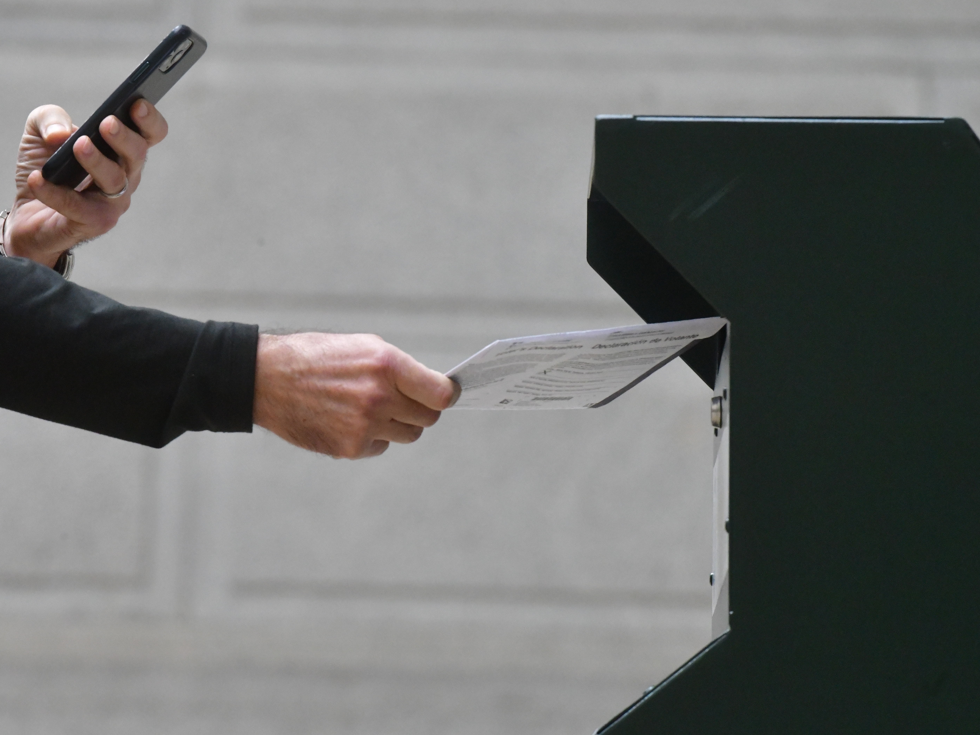 caption: A man photographs himself depositing his ballot in an official ballot drop box in Philadelphia on Oct. 27, 2020.