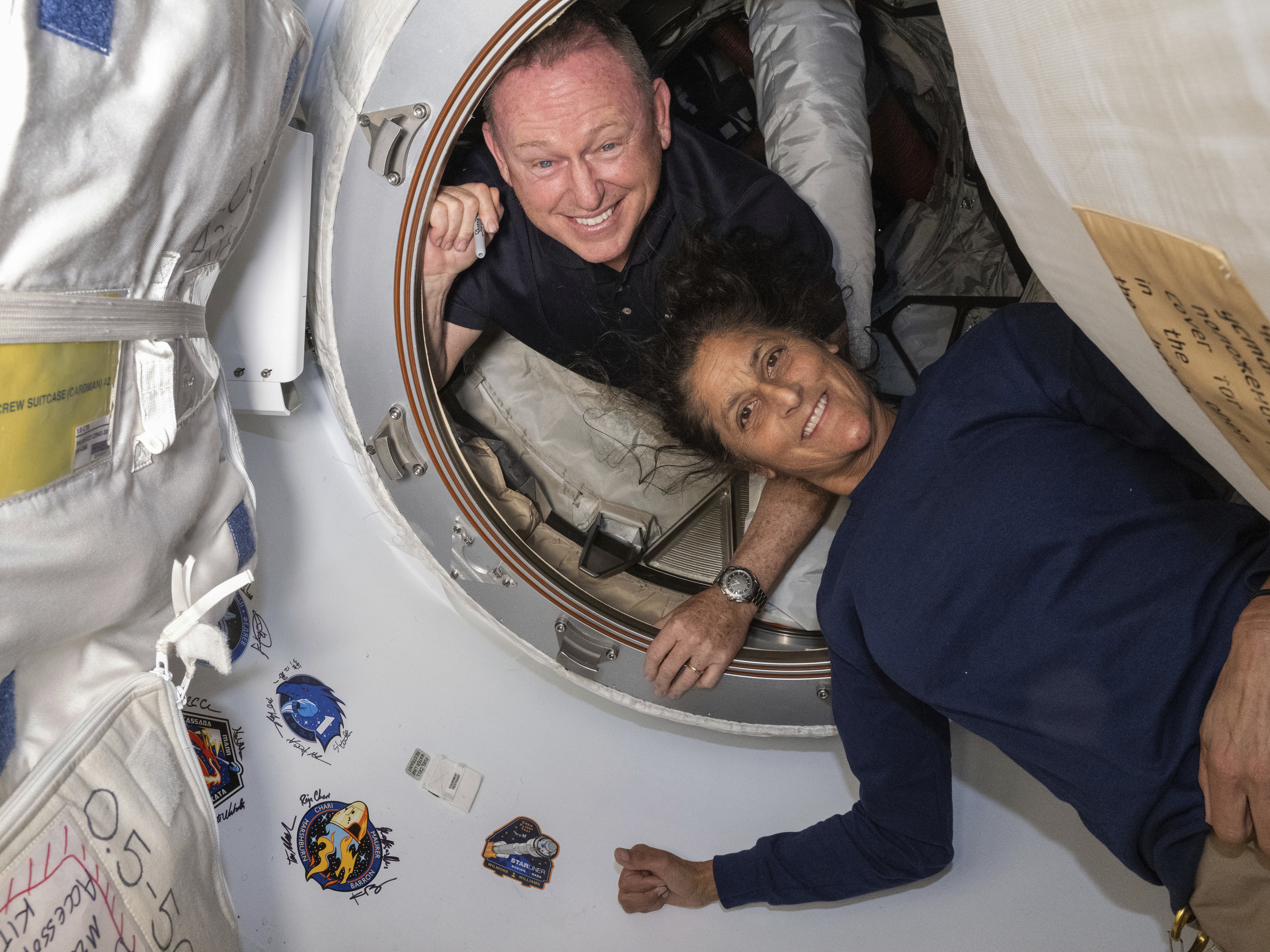 caption: In this photo provided by NASA, Boeing Crew Flight Test astronauts Butch Wilmore (left) and Suni Williams pose for a portrait inside the vestibule between the forward port on the International Space Station's Harmony module and Boeing's Starliner spacecraft on June 13.  