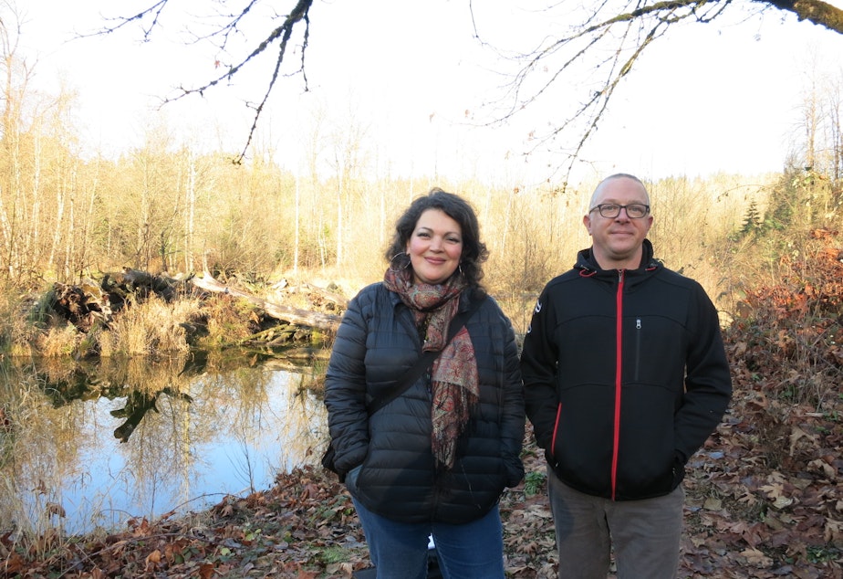 caption: KUOW listeners Meaghan Lodahl and Hans Reifenrath pose in front of the Cedar River. They live in Maple Valley and oppose a plan to relocate an asphalt plant across from where they're standing.