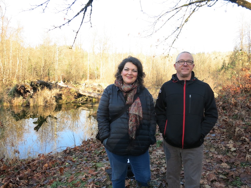 caption: KUOW listeners Meaghan Lodahl and Hans Reifenrath pose in front of the Cedar River. They live in Maple Valley and oppose a plan to relocate an asphalt plant across from where they're standing. 
