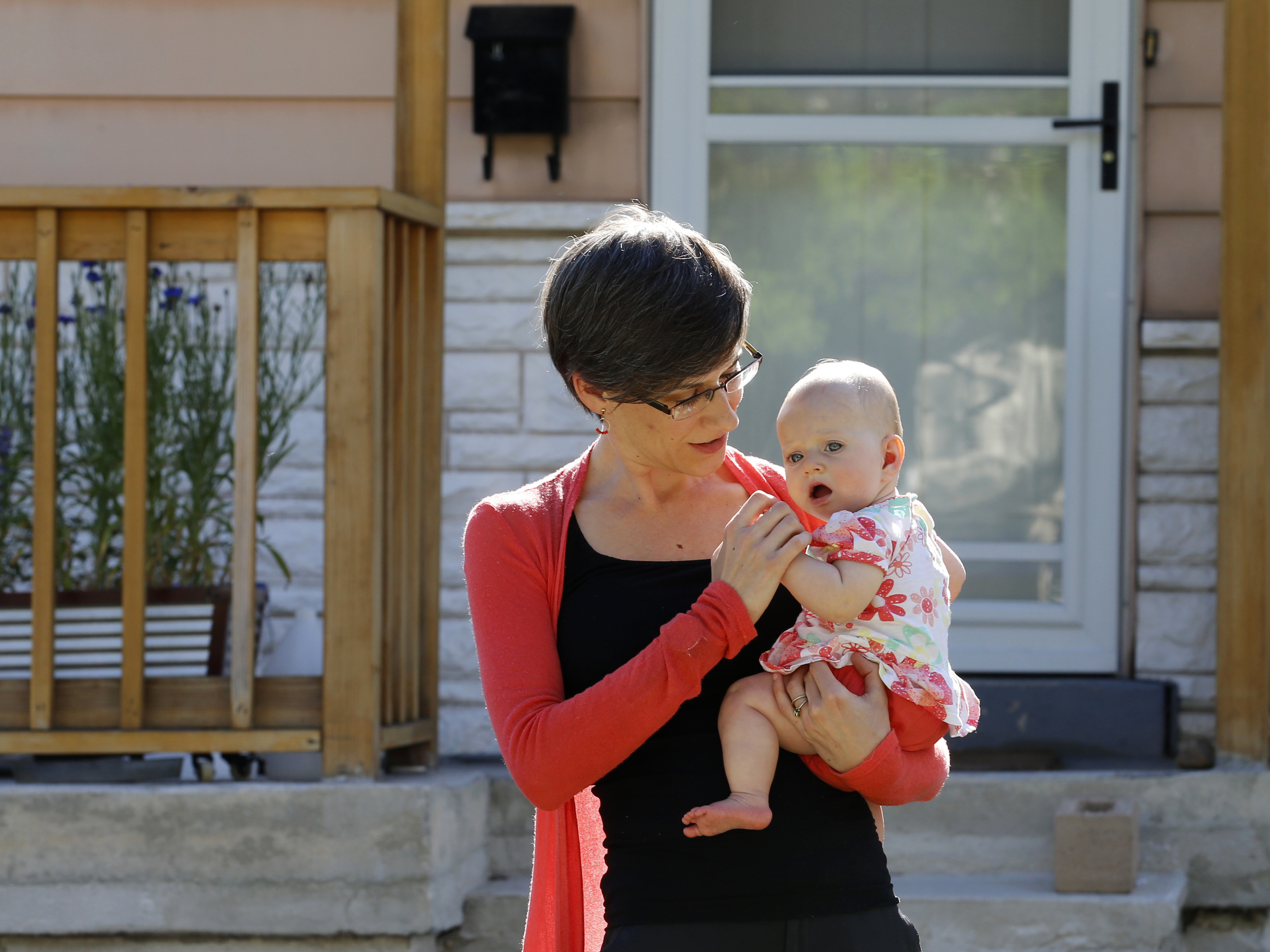 caption: In this Friday, May 29, 2020, photo, Sara Adelman holds her daughter Amelia in Salt Lake City. Adelman is burning through her vacation time to help manage her current status as a working-from-home mom since her daughter's daycare closed due to the coronavirus pandemic.