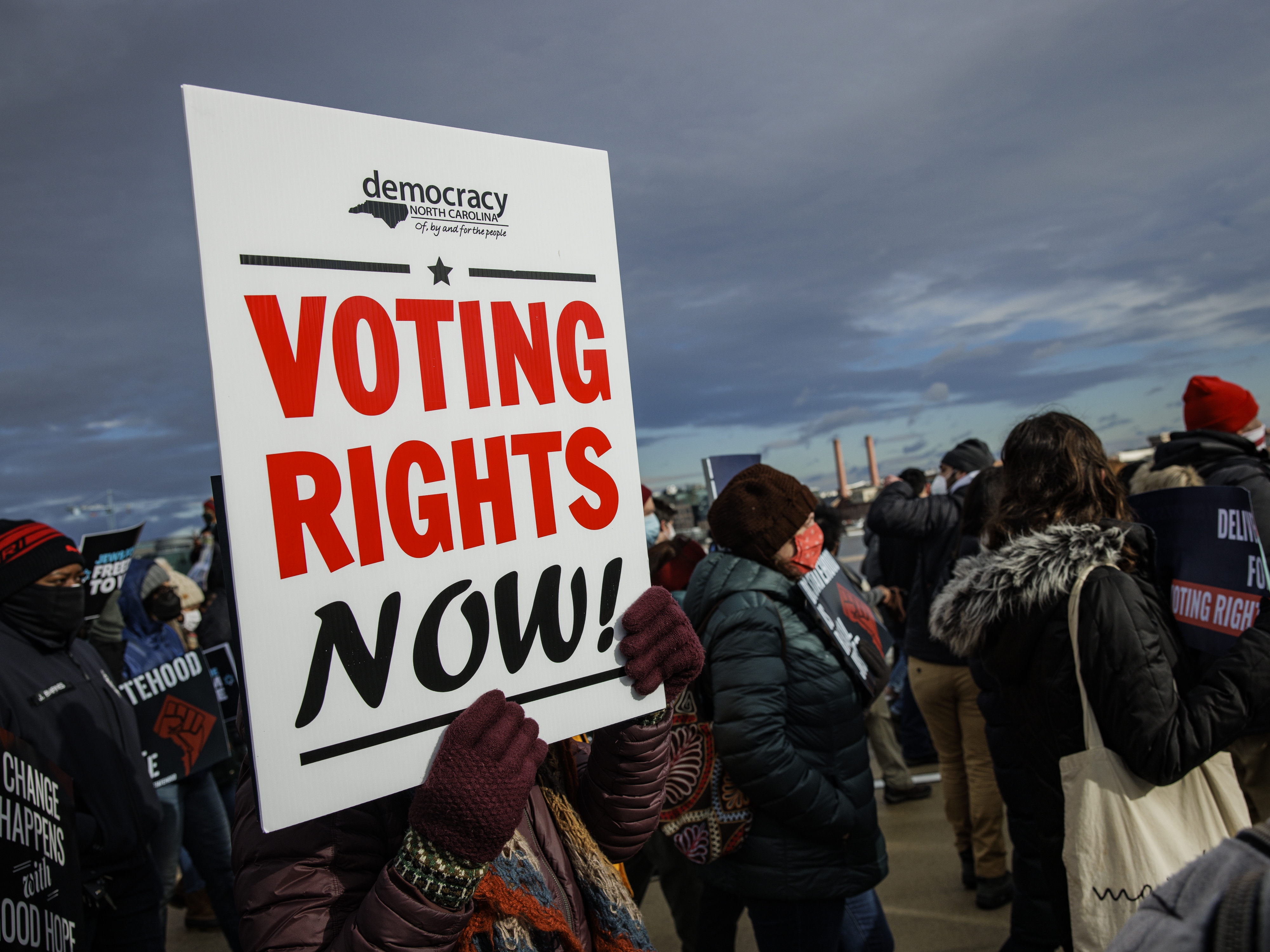 caption: A person holds a sign that says "VOTING RIGHTS NOW" during a peace walk in Washington, D.C., on Martin Luther King Jr. Day in 2022.
