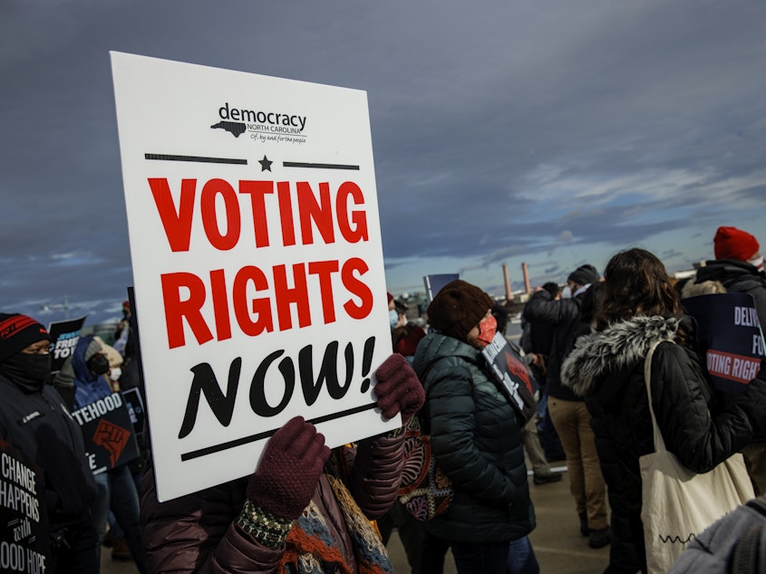 caption: A person holds a sign that says "VOTING RIGHTS NOW" during a peace walk in Washington, D.C., on Martin Luther King Jr. Day in 2022.