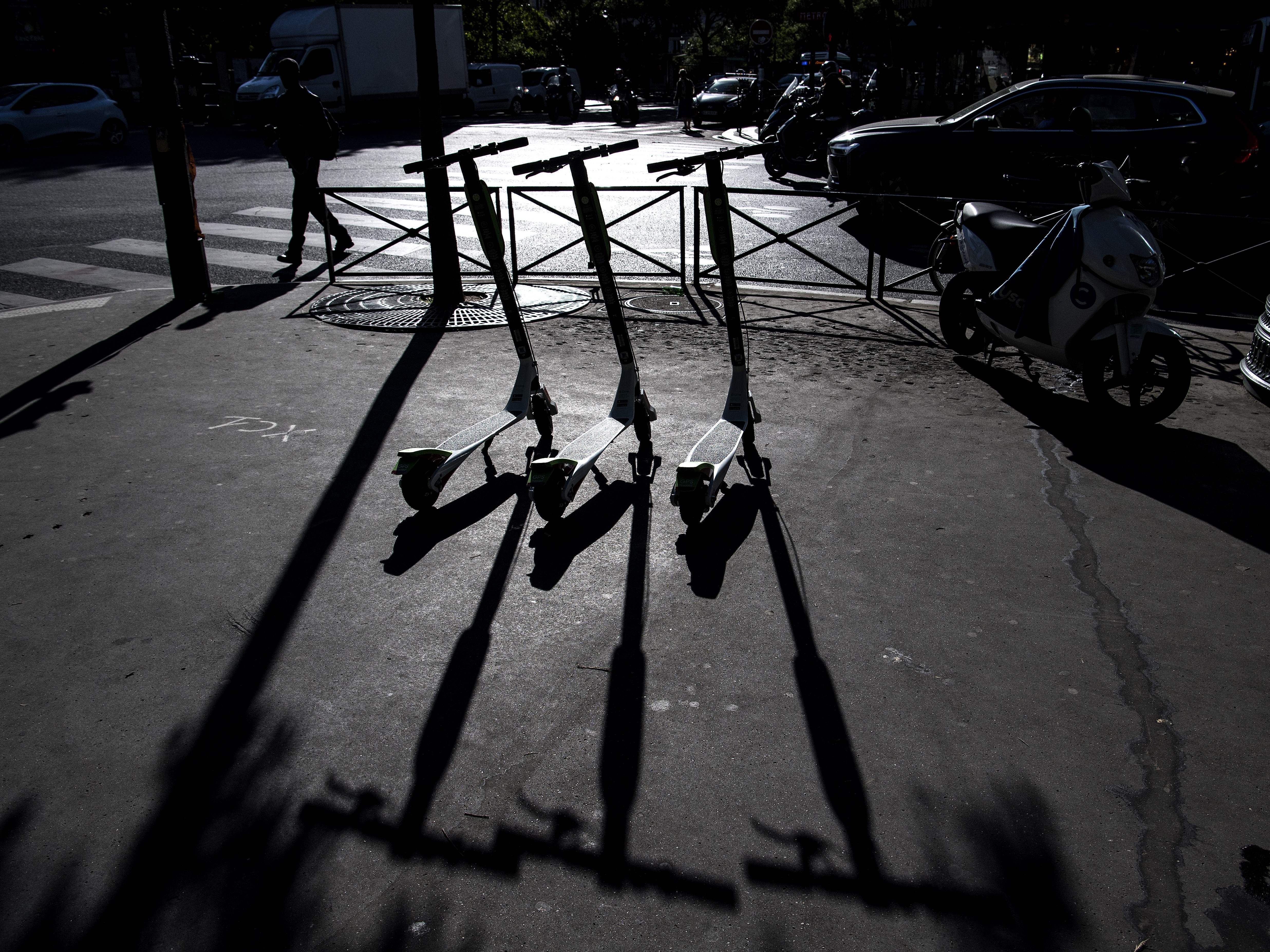 caption: Electric scooters are pictured on a sidewalk in Paris in June 2018. Multiple companies offer the small vehicles for rent by the minute in cities around the world, including many in the U.S.