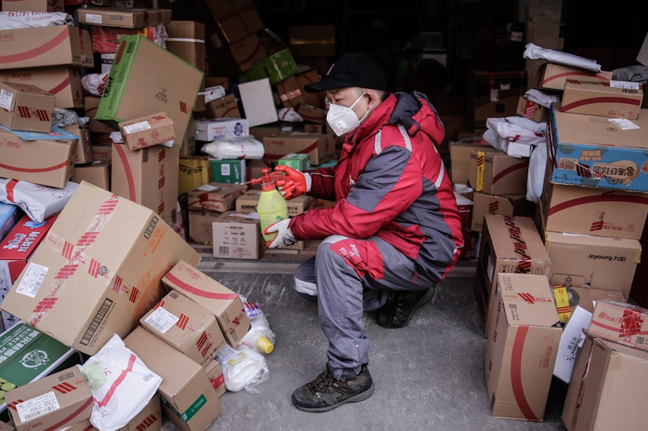 caption: A courier uses alcohol to disinfect packages in order to prevent any potential coronavirus pathogens from spreading to themselves and customers.