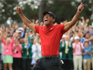 caption: Tiger Woods celebrates on the 18th green after winning the Masters at Augusta National Golf Club on April 14, 2019 in Augusta, Georgia.