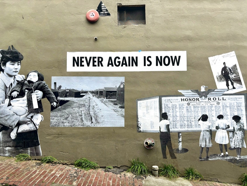 caption: A mural near the Panama Hotel in Seattle's Chinatown-International District proclaims, "NEVER AGAIN IS NOW."
