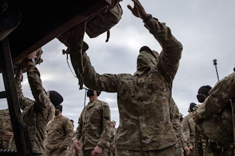 caption: U.S. Army soldiers retrieve their duffel bags after they returned home from a 9-month deployment to Afghanistan on December 10, 2020 at Fort Drum, New York. Earlier this month, President Biden announced that the U.S. would withdraw all its troops from Afghanistan by Sept. 11, 2021