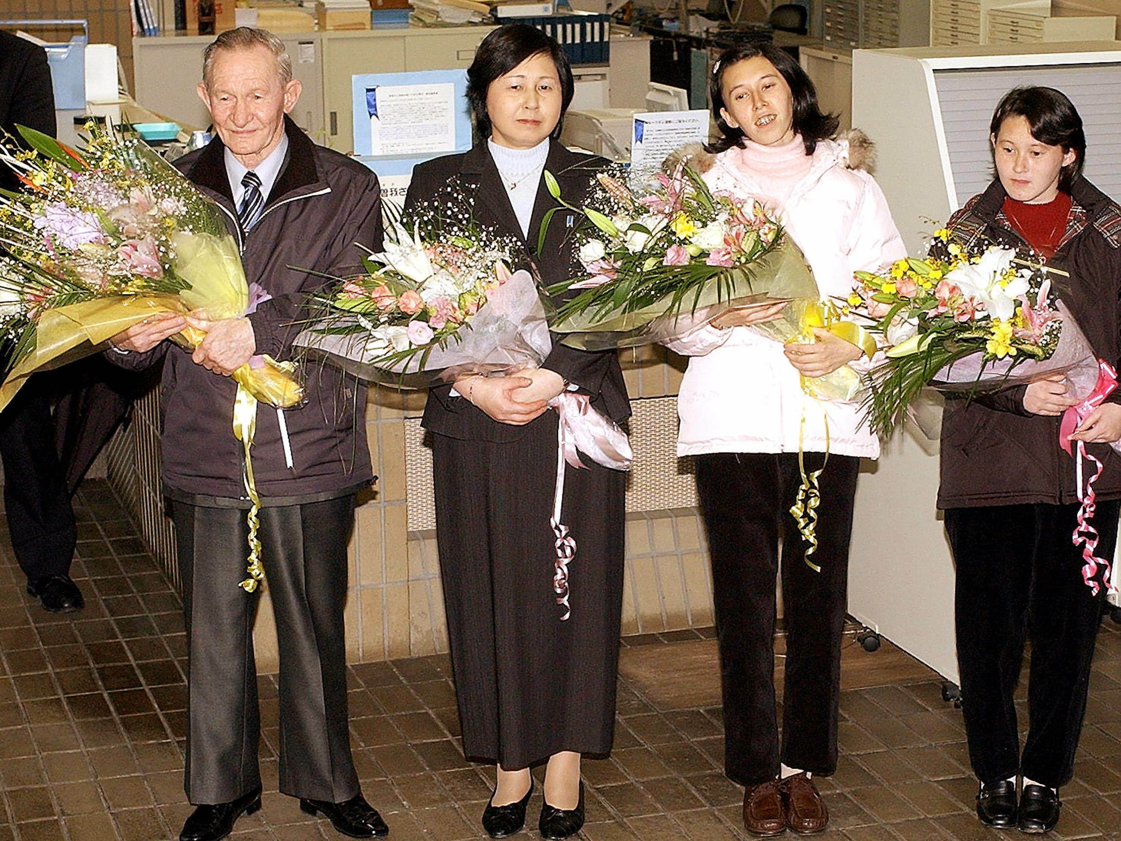 caption: Charles Jenkins (left), age 64, his wife Hitomi Soga (second from left) and their daughters arrive at Japan's Sado Island in December 2004, almost 40 years after he defected to North Korea.