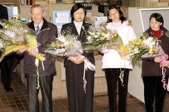 caption: Charles Jenkins (left), age 64, his wife Hitomi Soga (second from left) and their daughters arrive at Japan's Sado Island in December 2004, almost 40 years after he defected to North Korea.