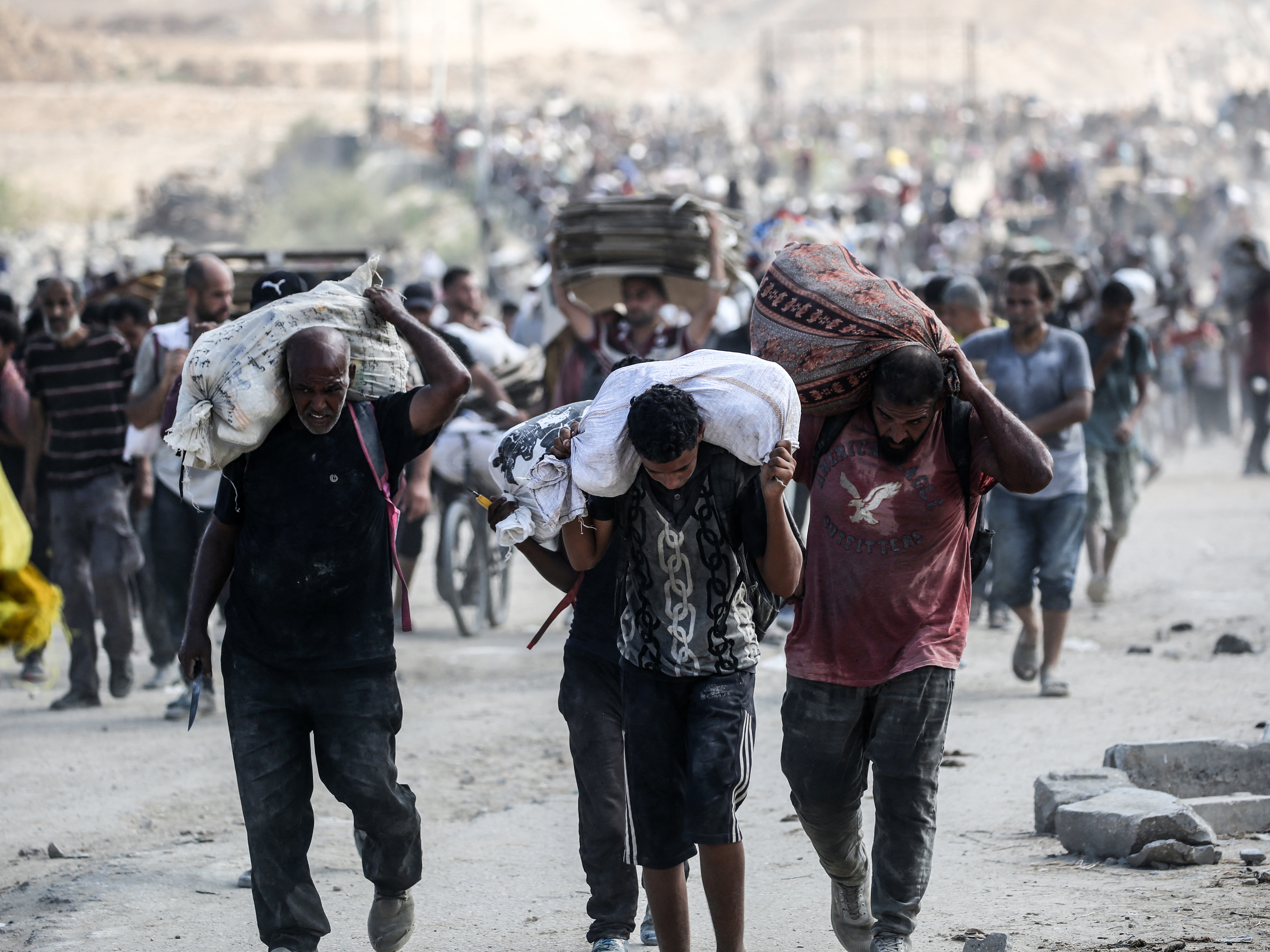 caption: Palestinians carry bags and folded cardboard boxes as they return from a food distribution point run by the U.S. and Israeli-backed Gaza Humanitarian Foundation group, near the Netsarim corridor in the central Gaza Strip on Saturday.