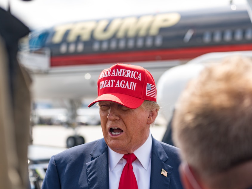 caption: Former President Donald Trump speaks to the media as he arrives at the airport on Wednesday in Atlanta, Georgia. Trump is visiting Atlanta for a campaign fundraising event he is hosting.