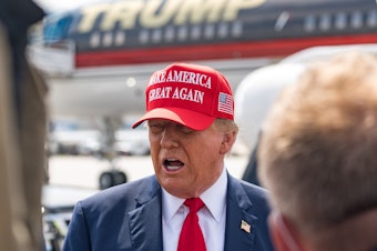 caption: Former President Donald Trump speaks to the media as he arrives at the airport on Wednesday in Atlanta, Georgia. Trump is visiting Atlanta for a campaign fundraising event he is hosting.