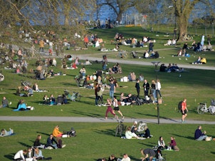 caption: People enjoy high temperatures on April 22 in Stockholm. Sweden has not imposed the extraordinary lockdown measures seen across Europe.