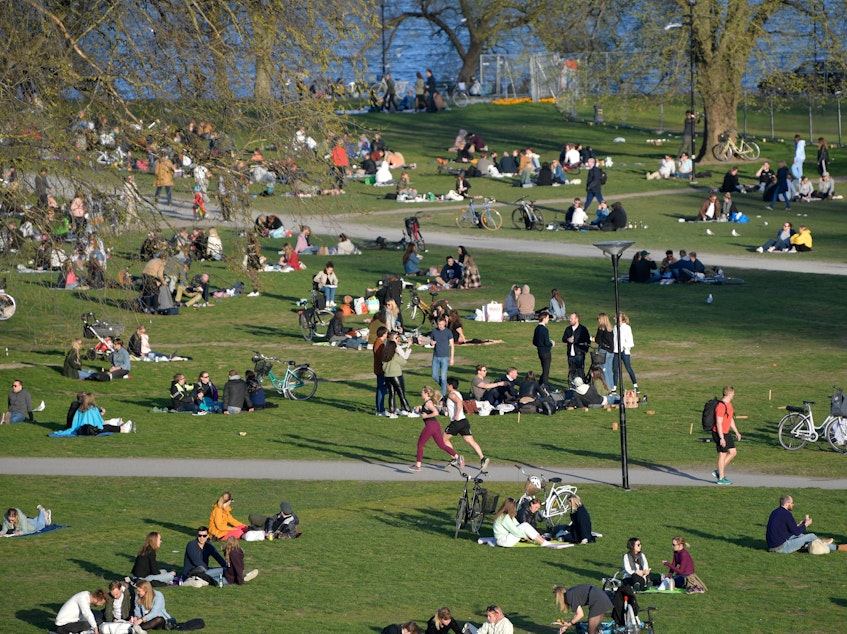 caption: People enjoy high temperatures on April 22 in Stockholm. Sweden has not imposed the extraordinary lockdown measures seen across Europe.