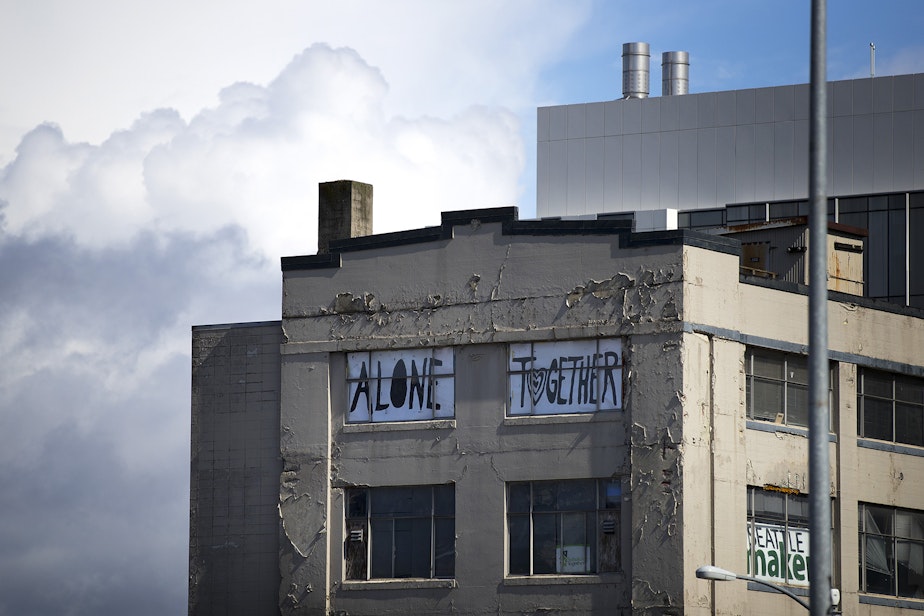 caption: 'Alone Together' reads a sign placed in the windows of a South Lake Union building, shown on Wednesday, March 25, 2020, in Seattle.