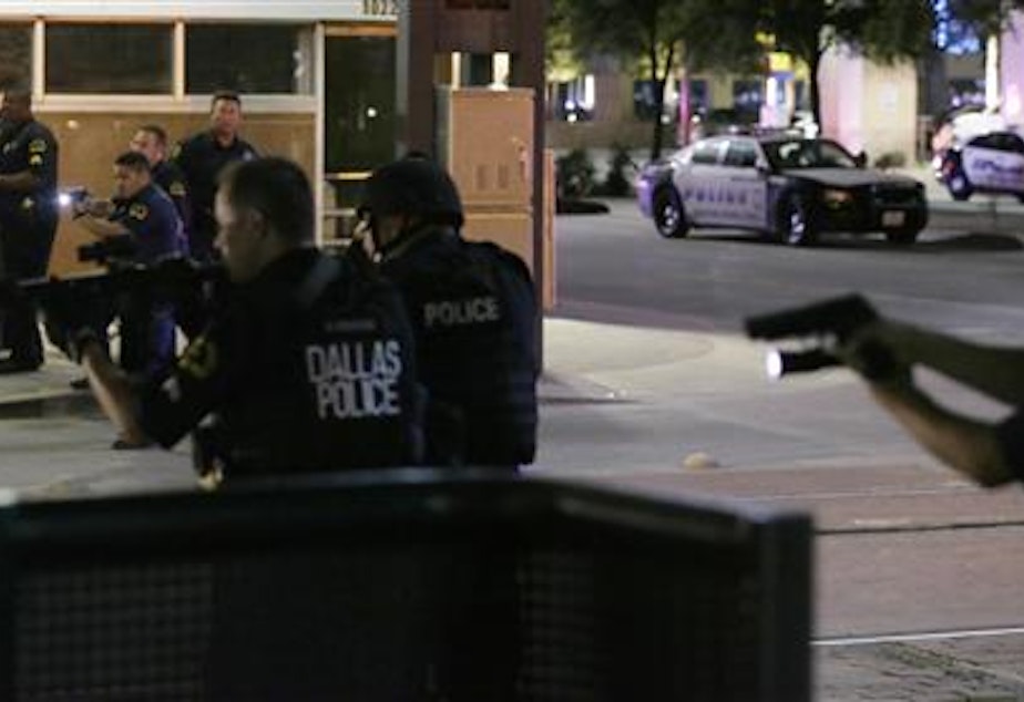 caption: Dallas police detain a driver after several police officers were shot in downtown Dallas, Thursday, July 7, 2016. Snipers apparently shot police officers during protests and some of the officers are dead, the city's police chief said in a statement.