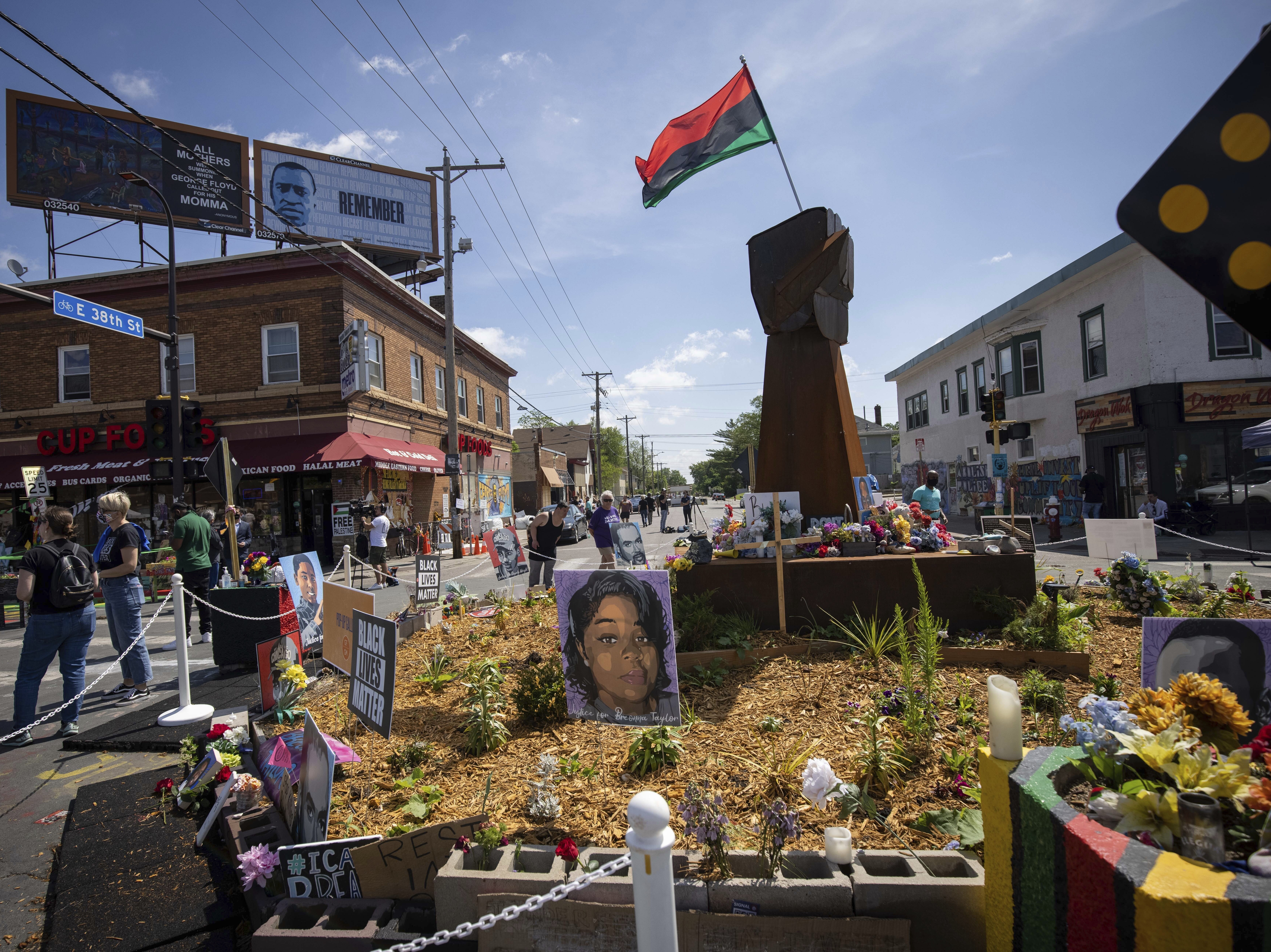 caption: People walk through George Floyd Square after shots were fired on the one year anniversary of Floyd's murder in Minneapolis, Minn. The intersection was disrupted by gunfire just hours before it was to be the site of a family-friendly street festival.