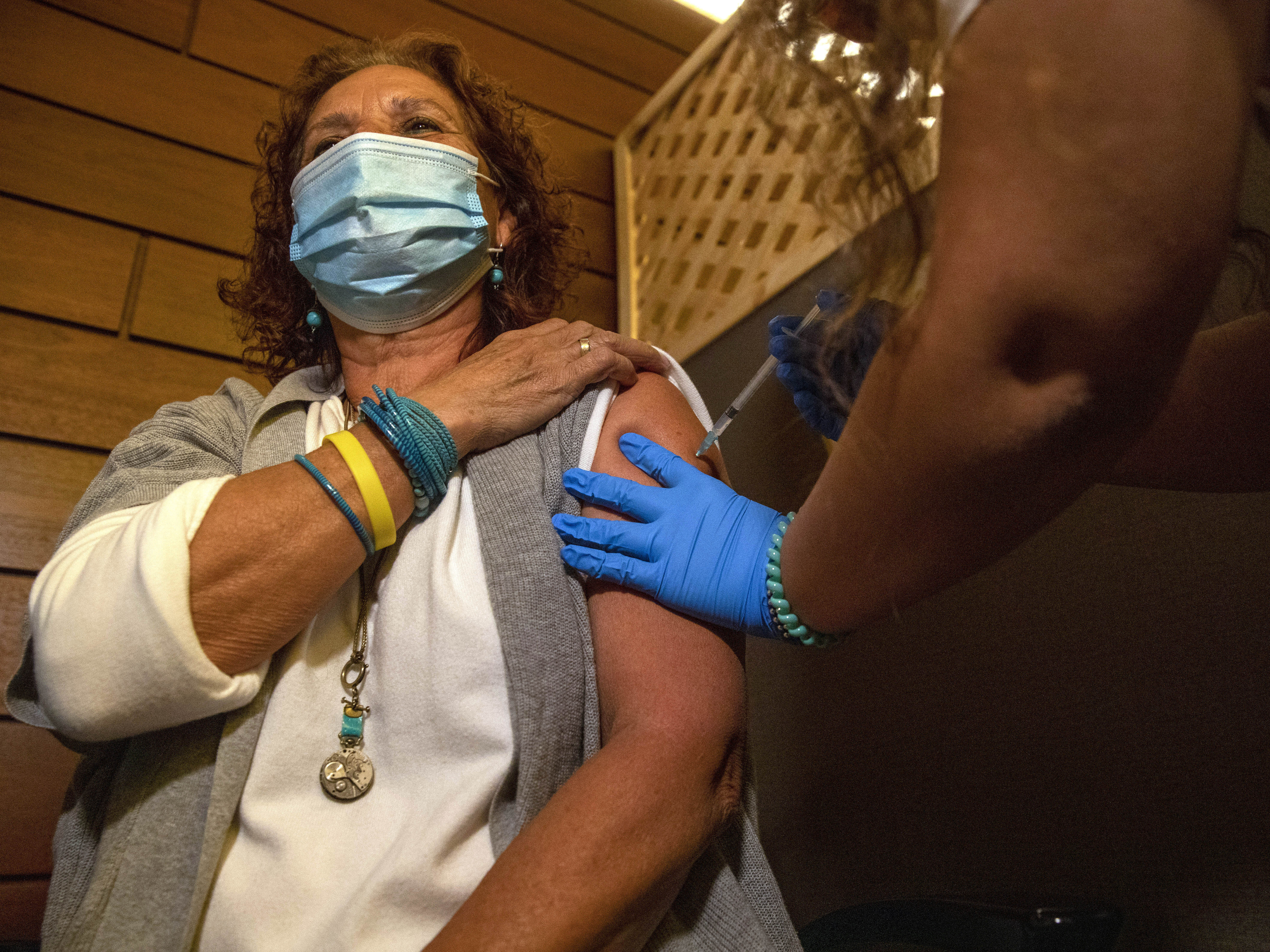 caption: Edna Halup, a staff member at a private nursing home, receives a Pfizer COVID-19 vaccine, in Ganei Tikva, Israel, on Dec. 22.