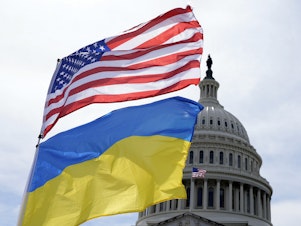 caption: The American and Ukrainian flags wave in the wind outside of the Capitol. The Senate is moving ahead with $95 billion in war aid to Ukraine, Israel and Taiwan.