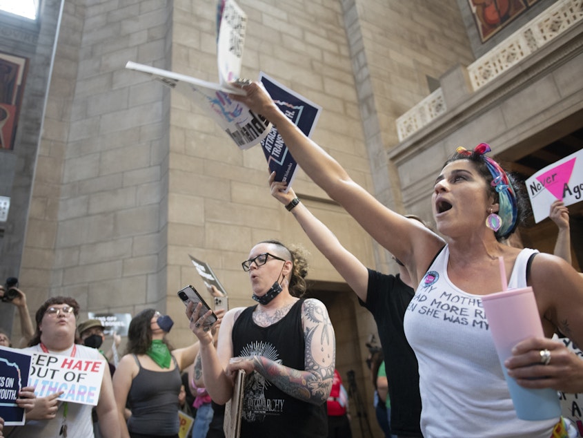 caption: Juju Tyner of Lincoln, right, leads the singing of "Over the Rainbow" during the protest of LB 574, which limits gender-affirming care for trans youth, on Friday, May 19, 2023, in Lincoln, Neb.