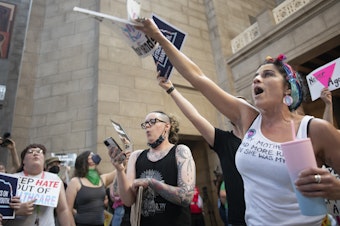 caption: Juju Tyner of Lincoln, right, leads the singing of "Over the Rainbow" during the protest of LB 574, which limits gender-affirming care for trans youth, on Friday, May 19, 2023, in Lincoln, Neb.