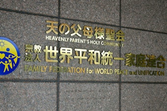 caption: The logo of the Family Federation for World Peace and Unification, widely known as the Unification Church, is seen at the entrance of its Japan branch headquarters in Tokyo. The Japanese government has asked a court to remove the church's legal status.