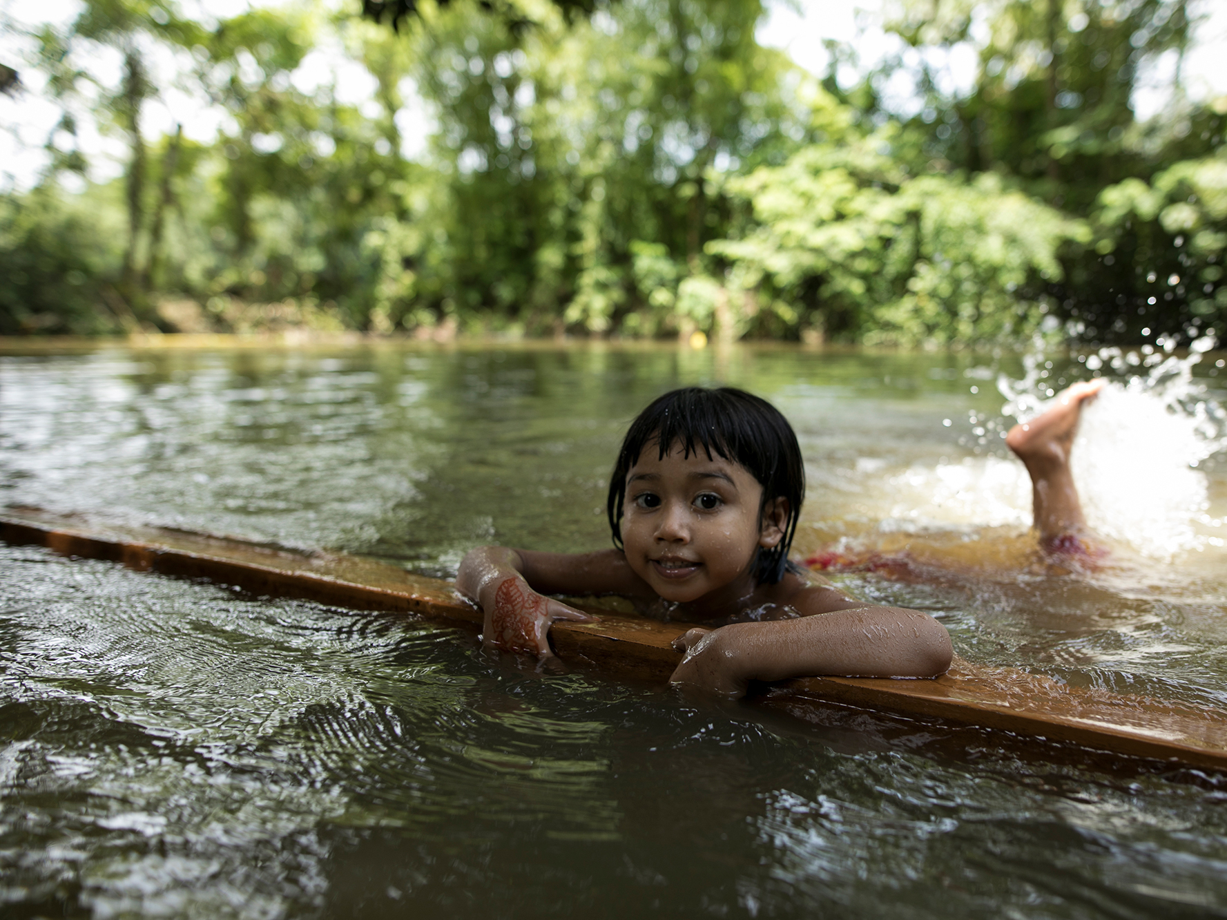 caption: A child learns to swim in a pond in a rural area of Bangladesh.