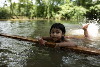 caption: A child learns to swim in a pond in a rural area of Bangladesh.