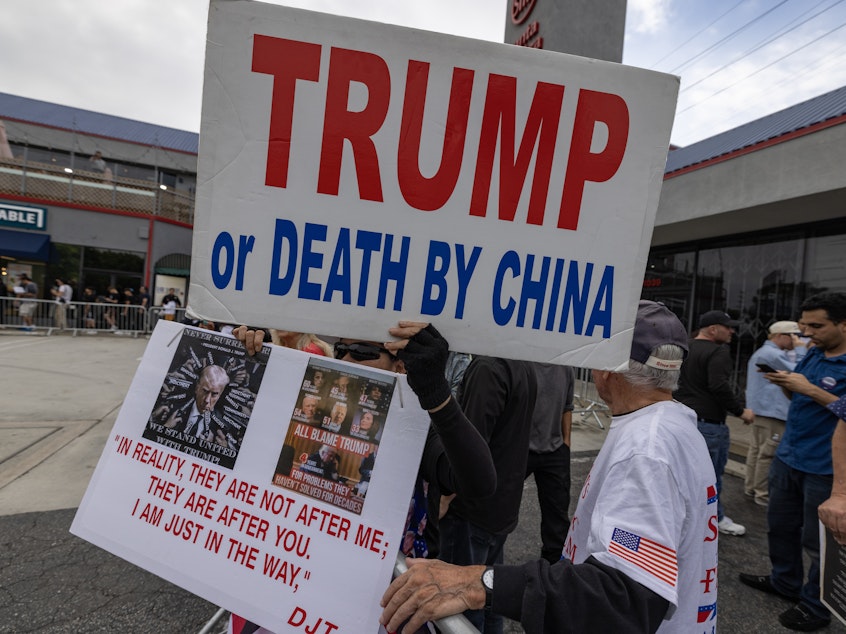 caption: Supporters of former President Donald Trump hold anti-China signs as Trump visits an ice cream shop during in September.