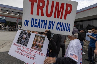 caption: Supporters of former President Donald Trump hold anti-China signs as Trump visits an ice cream shop during in September.