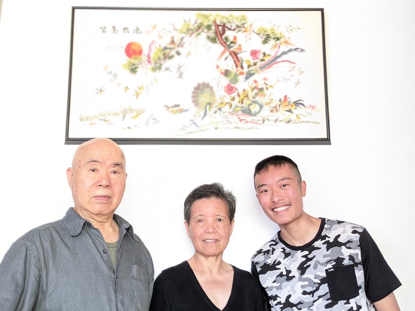 caption: Colin Yuen stands with his grandparents, Yuk and Cho Yuen, in their Beacon Hill home.