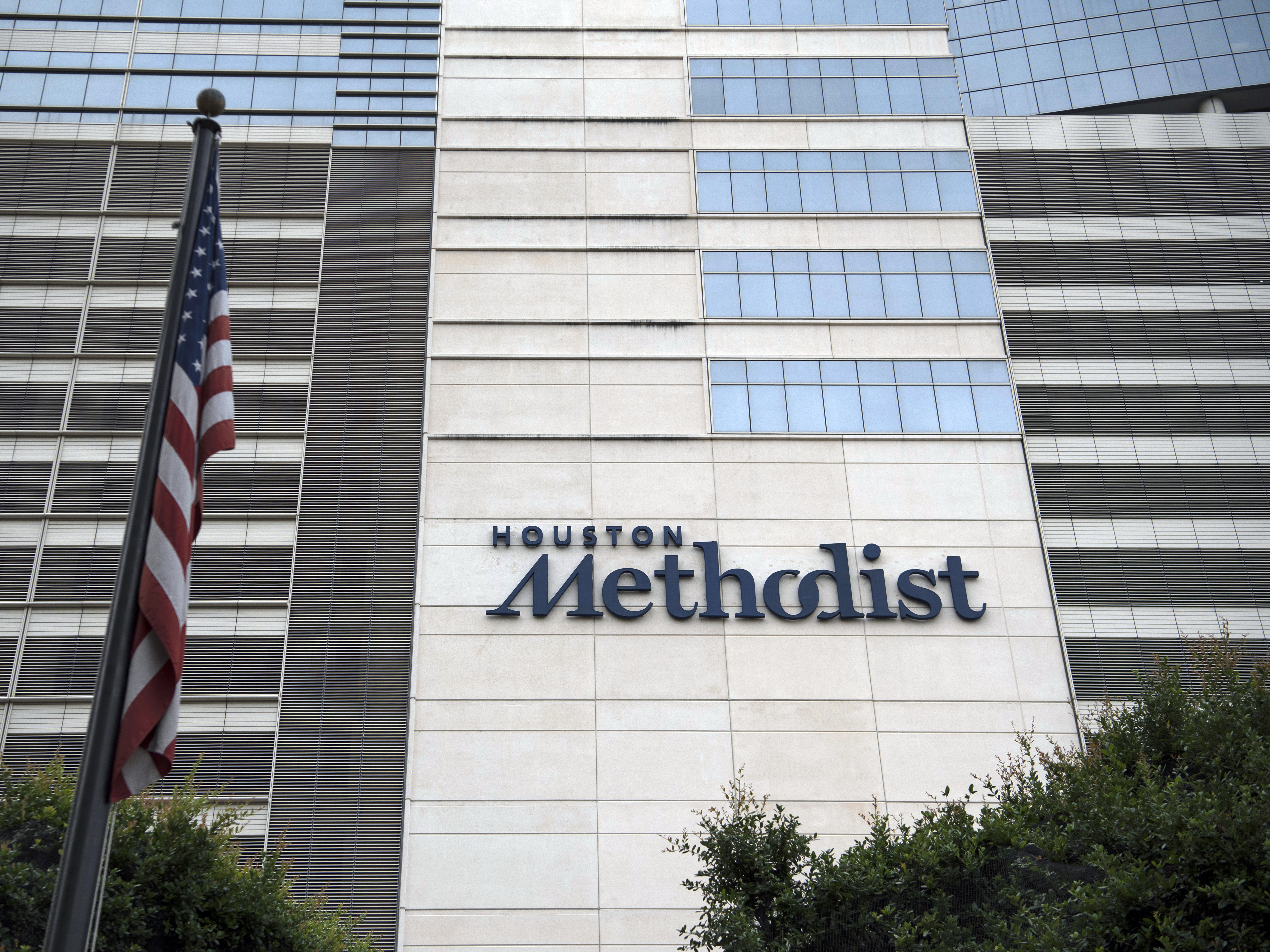 caption: An American flag flies outside the Houston Methodist Hospital at the Texas Medical Center (TMC) campus in Houston, Texas.