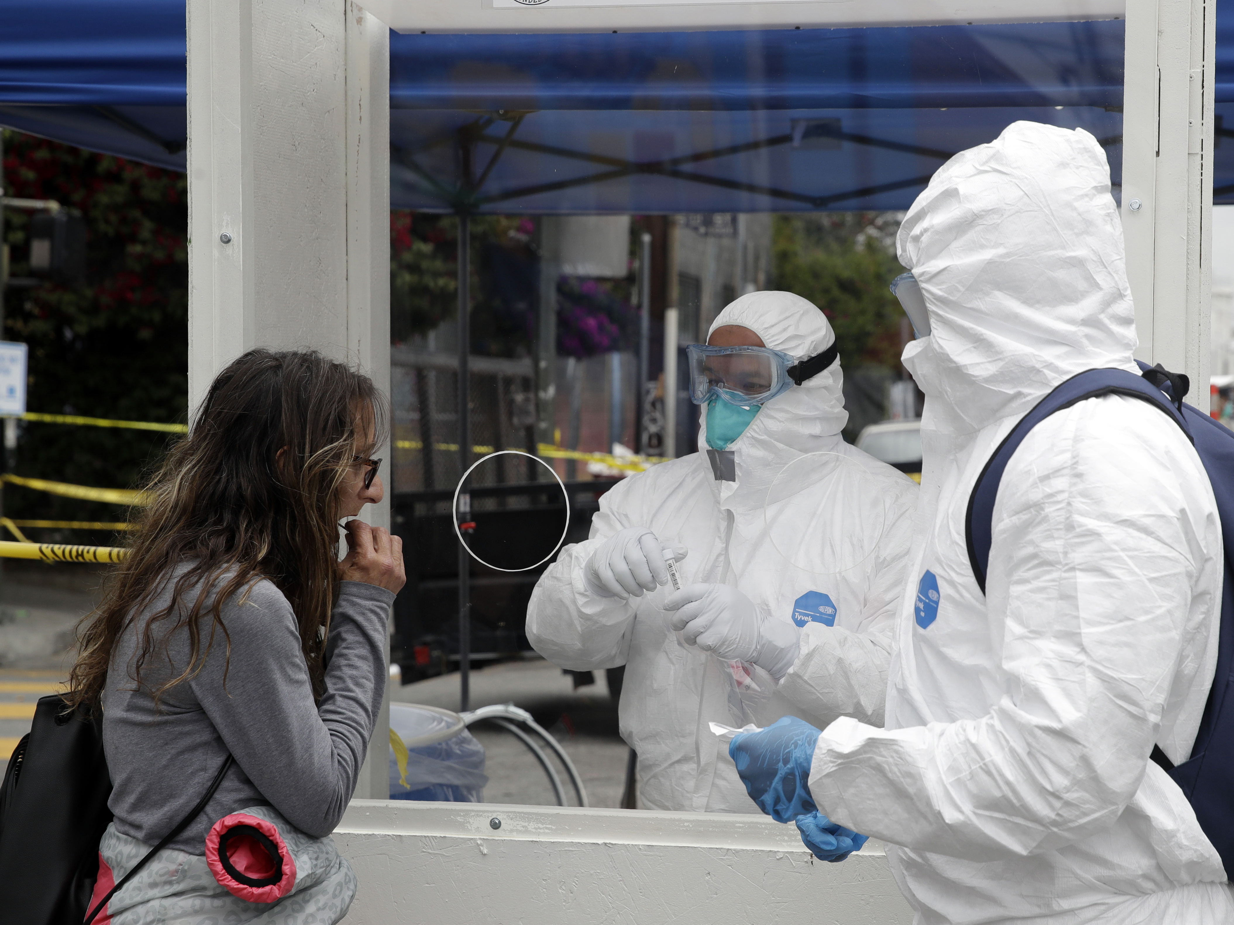 caption: Members of the Los Angeles Fire Department wear protective equipment as they conduct a novel coronavirus test on a woman, left, in Los Angeles earlier this month. The City of Los Angeles, in partnership with Los Angeles County, will offer free coronavirus testing to all residents regardless of whether they have symptoms.