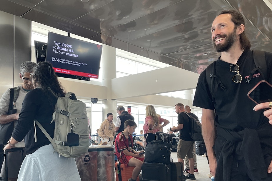 caption: Sam Adler of Seattle, right, waits for a delayed flight home from Denver International Airport on July 22, 2024.