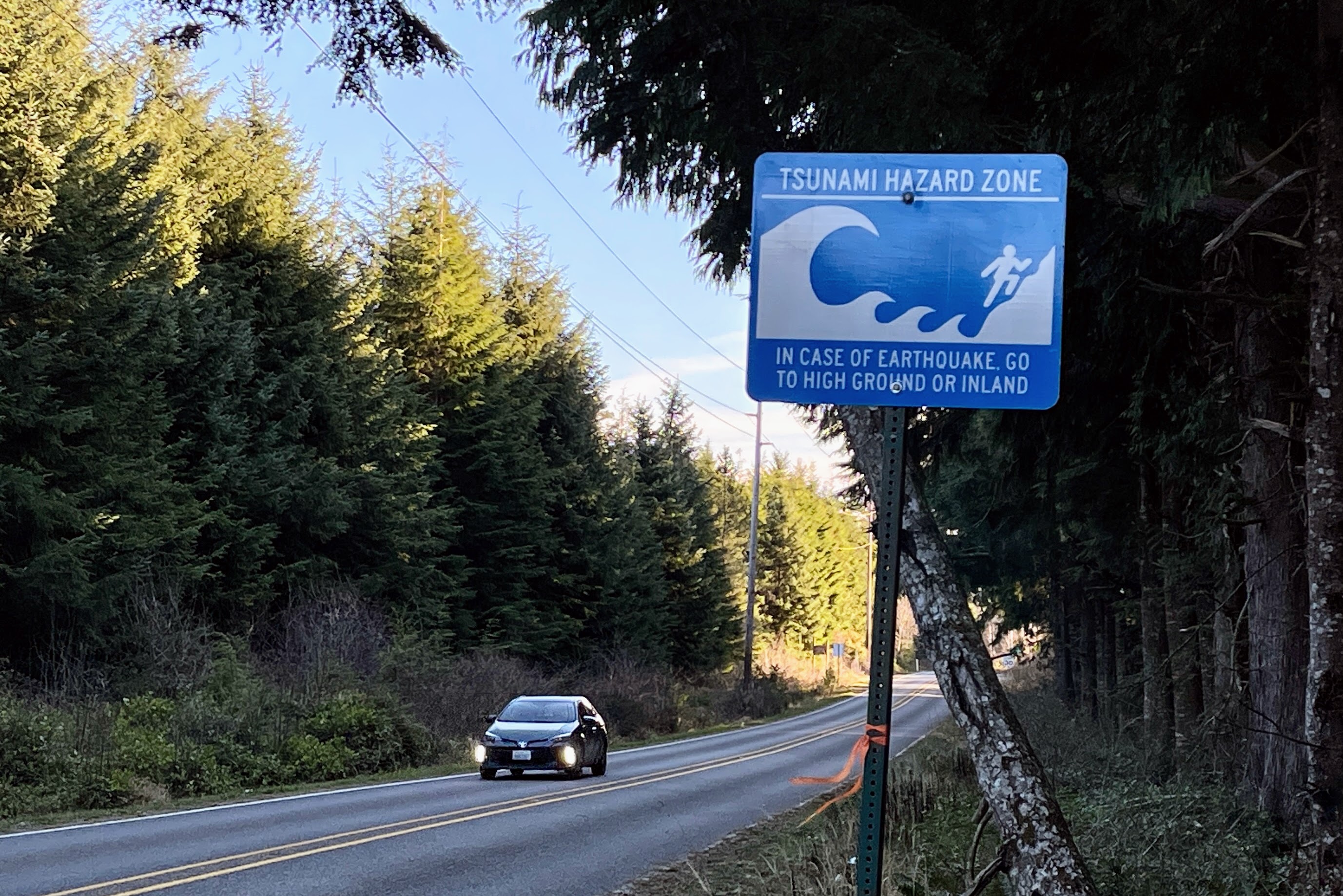 caption: A car exits a tsunami hazard zone on Washington Route 109 north of Moclips, on Jan. 12, 2024. 
