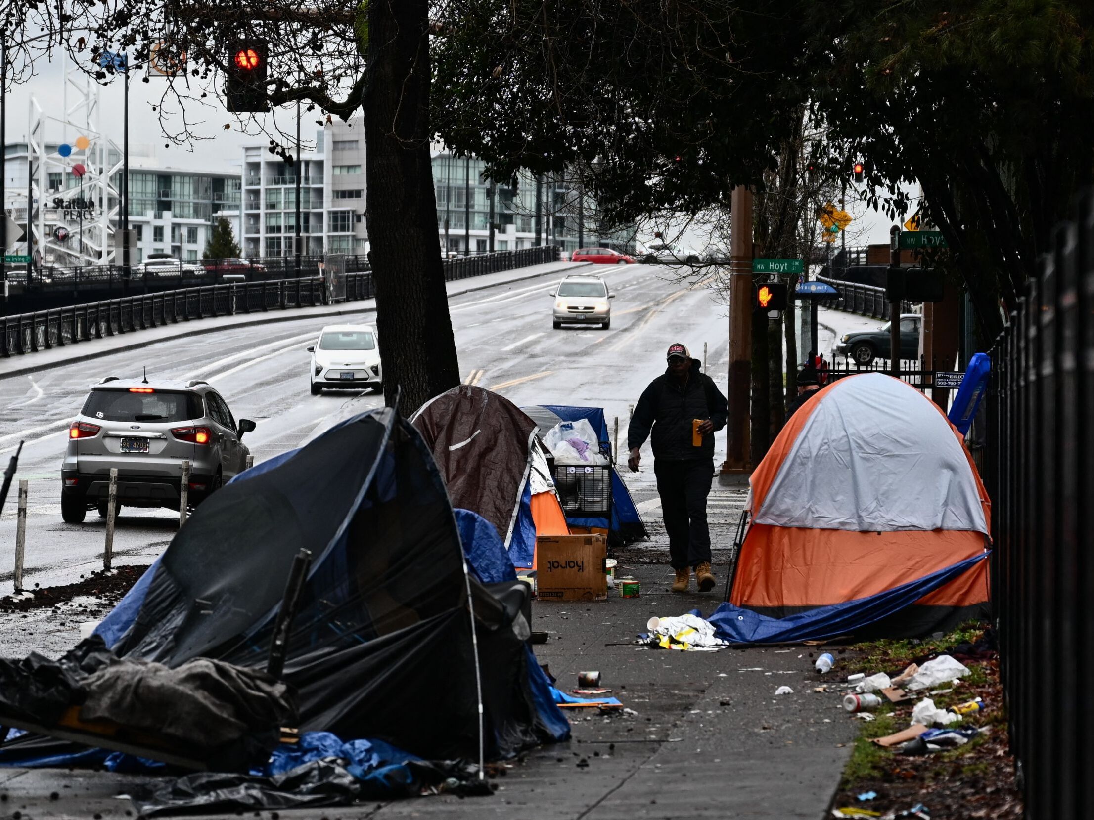 caption: A pedestrian walks past an encampment of tents after crossing Hoyt Street in Portland, Oregon on January 24, 2024.