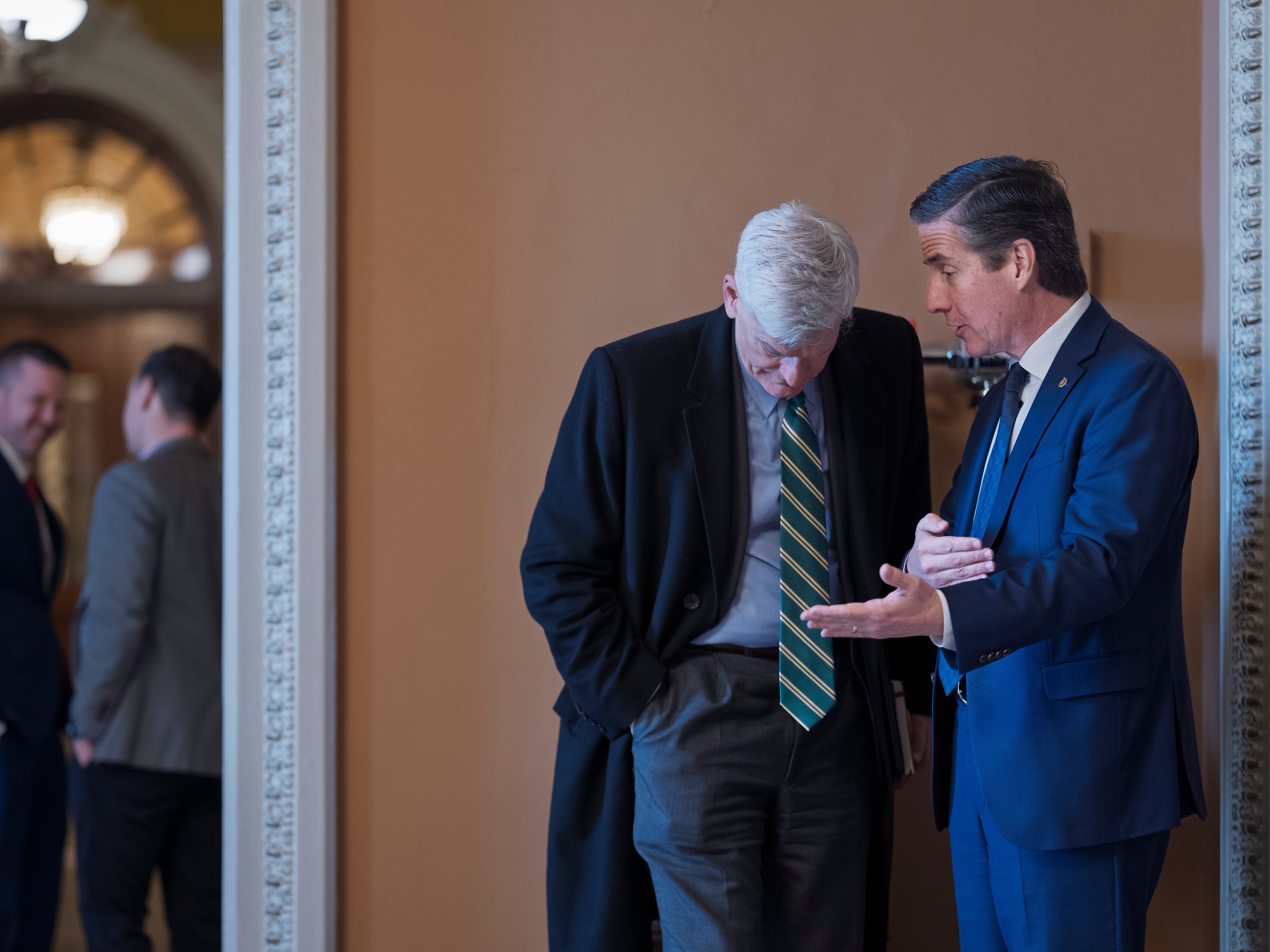 caption: Sen. Bernie Moreno (right), R-Ohio, and Sen. Bill Cassidy, R-La., are shown in a hallway of the Capitol talking. Cassidy is leaning down as Moreno speaks into his ear.
