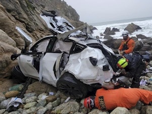 caption: Emergency personnel respond to a vehicle over the side of Highway 1 on Jan. 1, 2023, in California's San Mateo County. The driver who plunged off the treacherous cliff, seriously injuring himself, his wife and their two young children, has been charged with attempted murder.